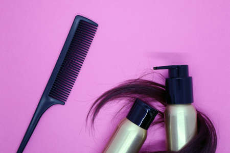 Lock of female light brown hair, hair care products on pink background. Top viewの写真素材