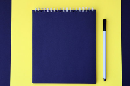 Mockup planner flat lay, top horizontal view yellow and black background. Black notepad with pen. Space for textの写真素材