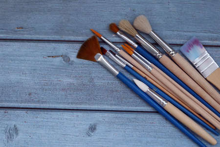 Set of artistic paintbrushes on blue wooden background. Top viewの写真素材