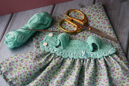 Crochet dress for a doll made of cotton yarn and textile. Home needlework made of thread. Knitting for toys.の写真素材