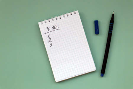 Notebook with to do list on green background and pen with copy space. white notesの写真素材
