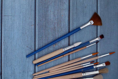 Set of artistic paintbrushes on blue wooden background. Top viewの写真素材