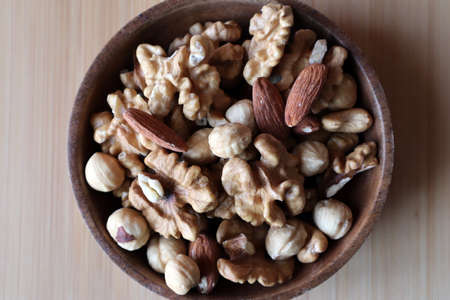 A mixture of nuts in a wooden bowl on a wooden board. Dried nuts. Snack