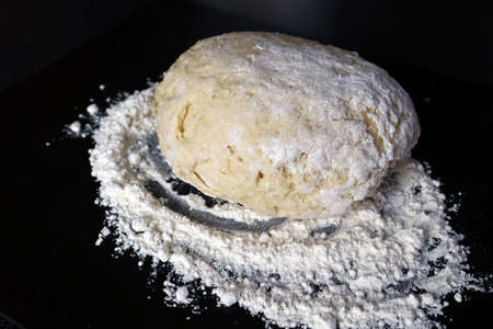Dough for making cottage cheese donuts, pies. Product made from flour for baking or frying in oil. Black background.の写真素材