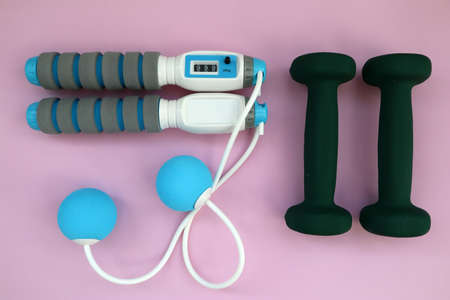 Athlete's set with dumbbells and skipping rope on pink background. top viewの写真素材