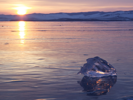 A piece of ice lying on the frozen surface of lake Baikal at dawn.の写真素材