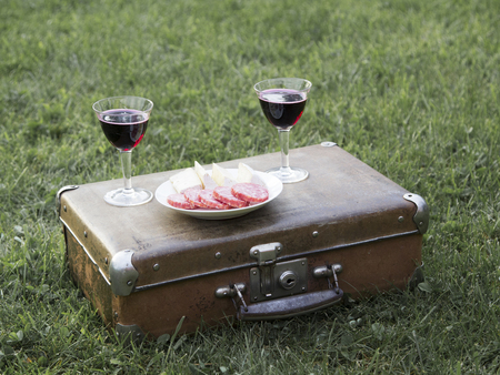 Romantic summer picnic on the grass with wine and a vintage suitcase.の写真素材
