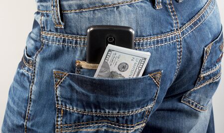 Money and mobile phone in a hip-pocket of trousersの写真素材