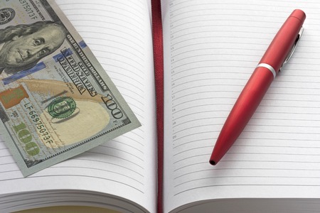 notebook, red pen and one hundred dollarsの写真素材