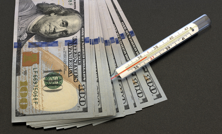 dollars and thermometer on a dark backgroundの写真素材