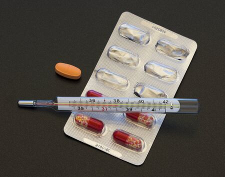 thermometer and pills on a dark backgroundの写真素材