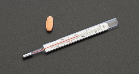 thermometer and pills on a dark backgroundの写真素材