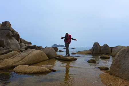 girl standing on a rock by the seaの写真素材