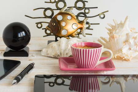 Mobile phone, tablet, coffee cup, seashell and fish on a wooden tableの写真素材