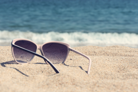 Glasses on the beach sand. Glasses on a background of sea wavesの写真素材