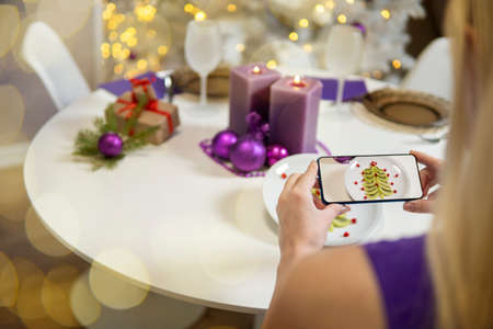 Girl's hand takes pictures of Christmas table. christmas table decoration. kiwi and pomegranate in...