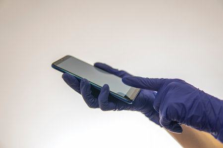 hands in medical gloves holds phone on a light background. high qualityの写真素材