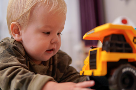 Little boy with blond hair plays with yellow truck on the floor. high qualityの写真素材
