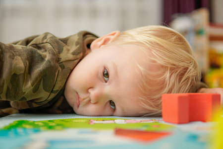 Little boy with blond hair lies sad on the floor. high qualityの写真素材