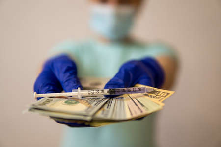hands in medical gloves keep money on which the syringe lies .. high qualityの写真素材