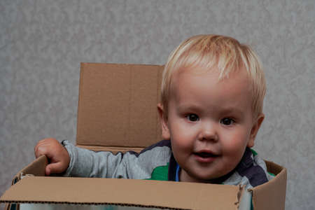 Little boy with blond hair sitting in a box. high qualityの写真素材