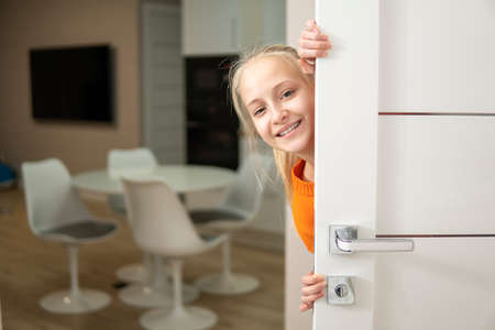 Girl peek out from behind the white door and laugh. high qualityの写真素材