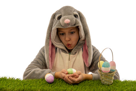 Girl in bunny costume look at Easter egg on green grass. isolated on white. easter holiday concept