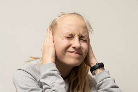 Teenage girl covers her ears in pain. deafness concept. high quality