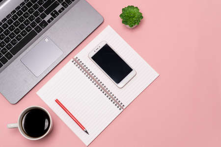flat lay, view from the top of the office desk table. Working space notepad, laptop, phone and coffee cup on a pink background. high qualityの写真素材