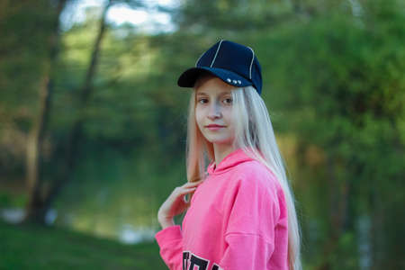 portrait of a teenage girl with blond hair in the background of a lake in a parkの写真素材