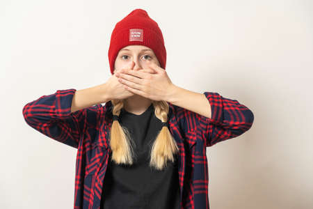 Girl close her mouth with her hands on a light background