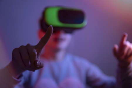 Teenage girl in virtual reality glasses in a dark room. partial focus on hands.の写真素材