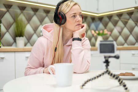 Girl blogger with blonde hair doing video on action camera in the house