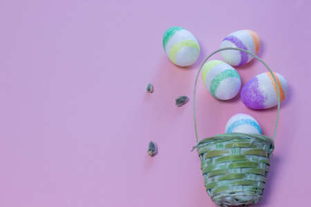 Wicker basket with Easter eggs on color background