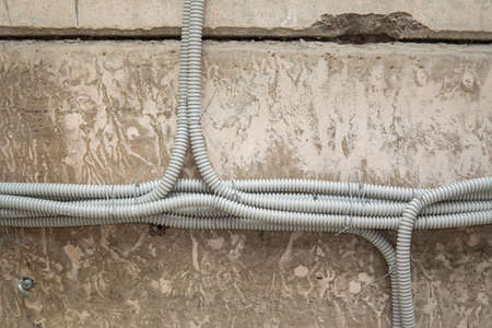 Aluminum tubing for wire protection lined up on old concrete wall.