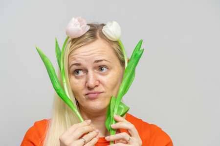 The girl holds tulips from her. Close up portrait of a beautiful girl with flowers near the face.の写真素材