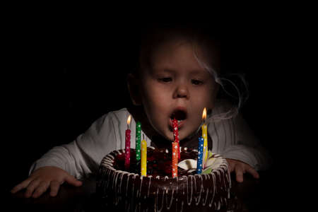 Birthday. A little sweet boy blows out candles on the stoke. dark background