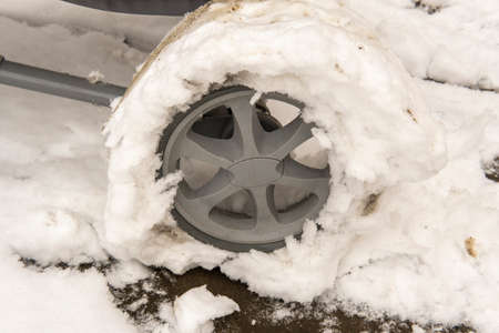 wheel of a baby carriage in the snow in spring. stalled.の写真素材