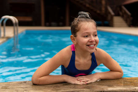 Pretty fair-haired girl eating watermelon on a wooden floor by the pool. Top view.