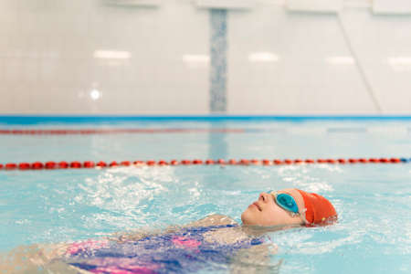 Girl swimming backstroke. open water competition among children. Sports and entertainment for...