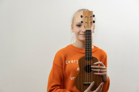 teenage girl with blond hair with guitar on grey backgroundの写真素材