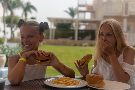 two teenage girls eating fast food and laughing.の写真素材