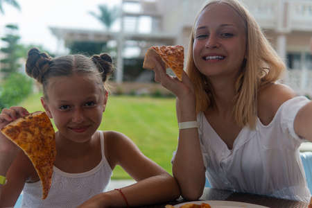 two teenage girls eating pizza and laughing.の写真素材