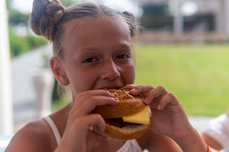 teenage girl eats a hamburger and laughs.の写真素材