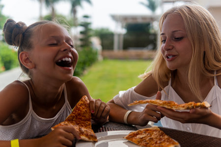 two teenage girls eating fast food and laughing.の写真素材