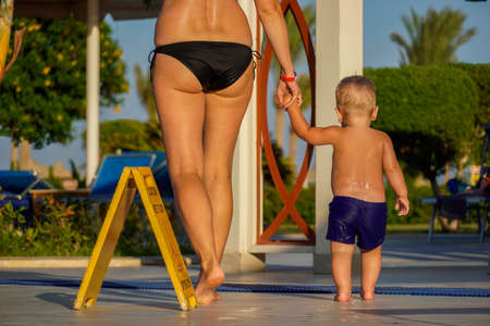 Little boy and mom go after swimming go on a wet floor.の写真素材