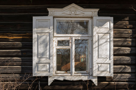 beautiful antique window in white frame on a wooden house.の写真素材