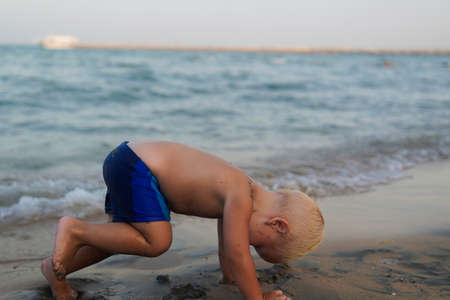 little boy with blonde hair having fun on the beach.