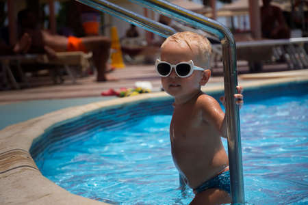 little boy with blonde hair coming out of the pool.