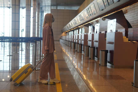 teenage girl with blonde hair standing near the information board to the airport.の写真素材